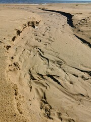 sandy shore of the lake prints of human footprints and water flows