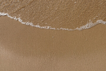 Obraz na płótnie Canvas Low tidal waves with ripples and foam on sea coast