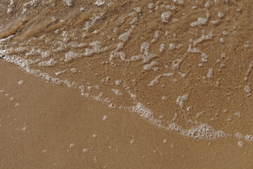 Low tidal waves with ripples and foam on sea coast