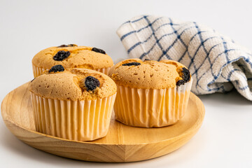 Group of homemade raisin sponge cupcake in wooden tray.