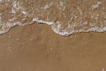 Fototapeta na wymiar Tidal waves with ripples and foam on sea coast