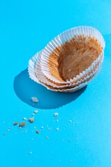 Paper capsules for cupcakes. Empty paper cupcake molds and scattered crumbs from eaten cupcakes on...