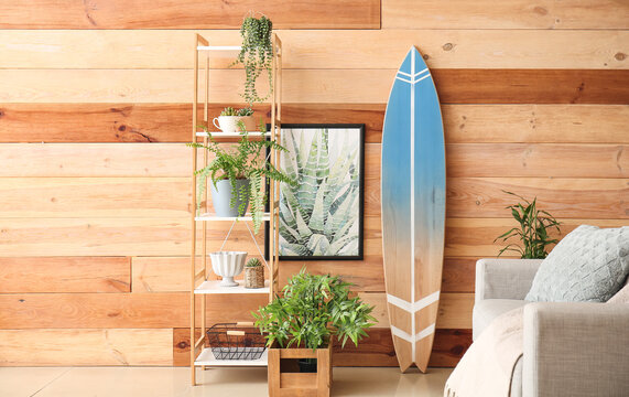 Interior of modern stylish room with sofa, shelf unit and surfboard