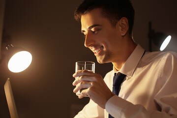 Businessman drinking water while working in office late at night