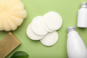 Cotton pads and cosmetic products on color background