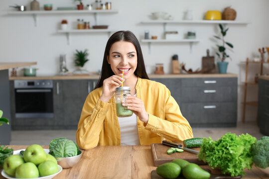 Young Woman Drinking Healthy Green Smoothie In Kitchen