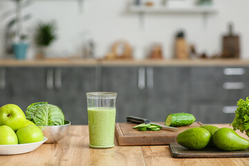 Glass of healthy smoothie and ingredients on kitchen table, closeup
