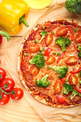 Parchment with tasty vegetarian pizza on light wooden background