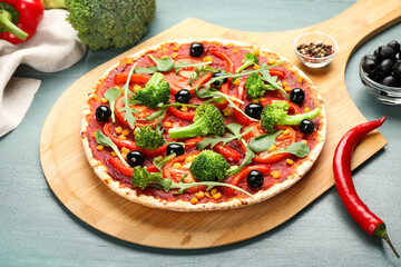 Board with tasty vegetarian pizza and chili pepper on color wooden background