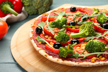 Board with tasty vegetarian pizza on color wooden background, closeup