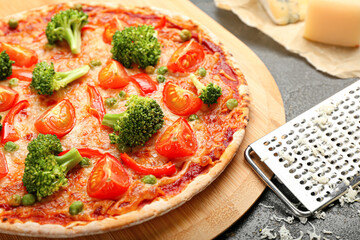 Board with tasty vegetarian pizza and grater on dark background, closeup