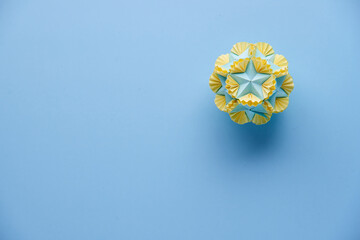 Multicolor handmade modular origami ball or Kusudama Isolated on blue background. Visual art, geometry, art of paper folding, paper crafts. Top view, close up, selective focus, copy space.