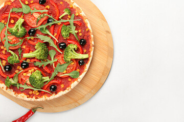 Board with tasty vegetarian pizza on light background