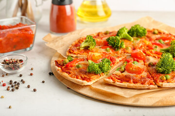 Board with tasty vegetarian pizza, sauce and peppercorn on light background
