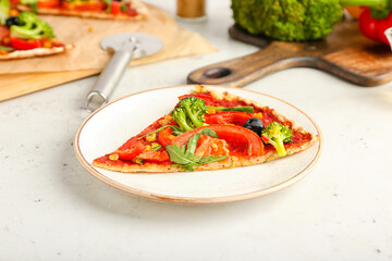 Plate with slice of tasty vegetarian pizza on light background, closeup