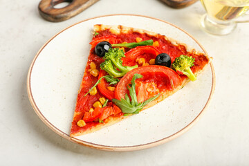 Plate with slice of tasty vegetarian pizza on light background, closeup