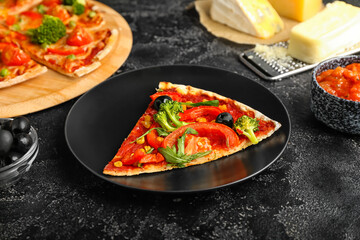 Plate with slice of tasty vegetarian pizza on dark background, closeup