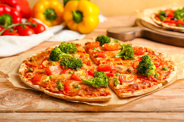Parchment with tasty vegetarian pizza on wooden background