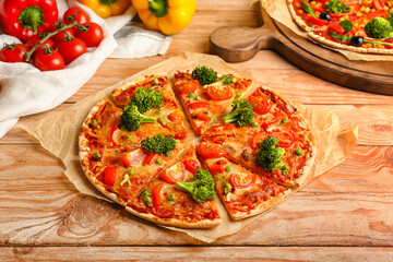 Parchment with tasty vegetarian pizza on wooden background