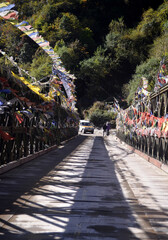 Prayer flags flutter at iron bridge amid vehicle trying to enter the bridge looks mesmerizing at Lachung in North Sikkim. This is the most beautiful place of Sikkim as throng here largely every year.