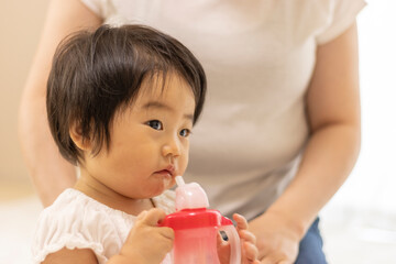 ストローでお茶を飲む赤ちゃん（1歳、日本人、女の子）