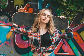 Woman riding a skateboard on colorful street art. Skater girl on a longboard. Cool female skateboarder at sunset. Carefree female skater 20s enjoying freedom youth lifestyle Hobby © anna.stasiia