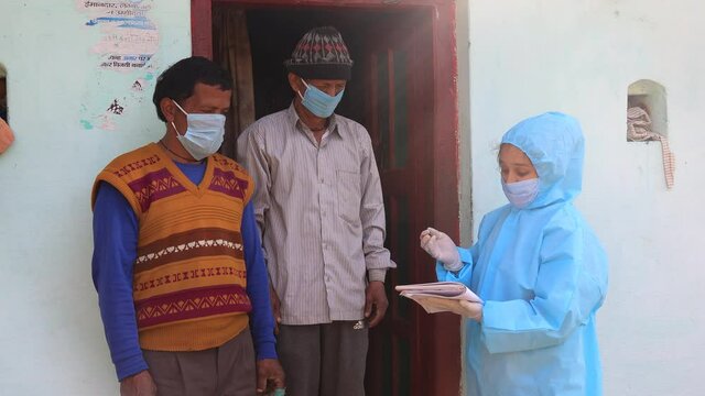Women nurse workers in ppe kit doing door to door surveys in Indian village regarding Covid-19