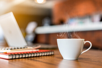 Blurred of cup of hot coffee on wooden table with computer