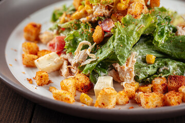 Russian malibu salad with croutons and ham on wooden background