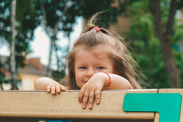 Kid on obstacle course. Pretty happy young girl playing outside in playground. Portrait Of Cute...