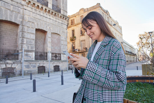 Trendy young woman messaging on smartphone on street