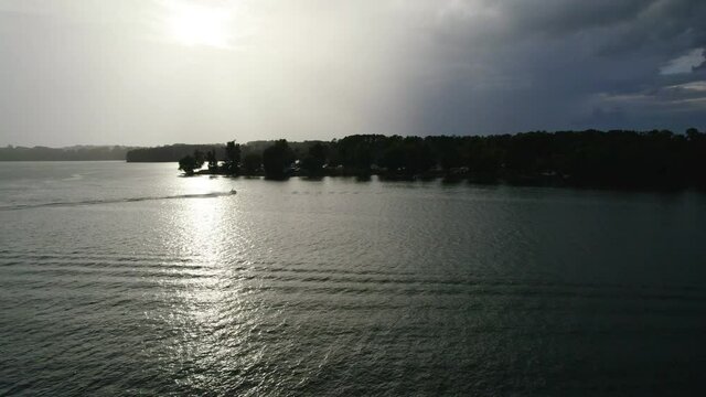 Aerial view of Lake with shiny water and green trees. Sun reflection in the water. Beautiful spring landscape with trees