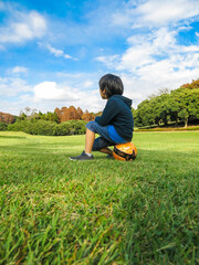 晴れた日に芝生の公園でボールに座るサッカー少年