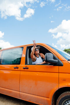 Content traveling woman peeing out of car in nature