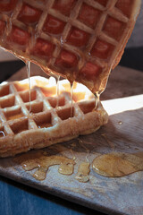 waffle with honey falling on wooden table