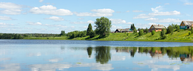 Beautiful rural landscape. Small village by the lake on a sunny summer day.