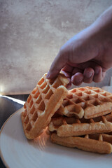 Hand taking a artisan waffle of a with plate