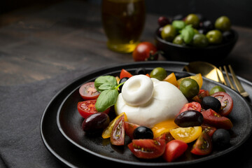Italian fresh burrata cheese with tomatoes and olives. Caprese salad with mozzarella tomatoes and basil
