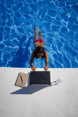 bird view of remote online working digital nomad woman in bikini with long black hair and laptop on...