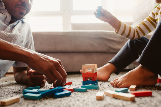 Anonymous father and son playing with construction pieces in the dining room