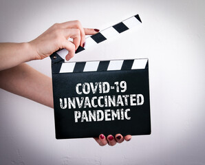 Covid-19 unvaccinated pandemic. Female hands holding movie clapper