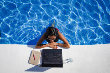 bird view of remote online working digital nomad woman in bikini with long black hair and laptop on...