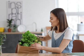 Young woman with fresh vegetables in kitchen