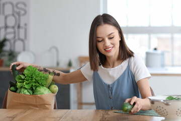 Young woman with fresh vegetables in kitchen