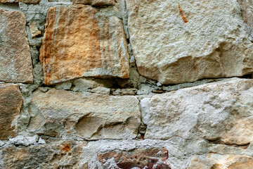Old natural stone wall on background. Brick wall with ancient masonry. Full frame of rich and varied texture close up.