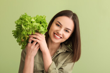 Young woman with fresh lettuce on color background