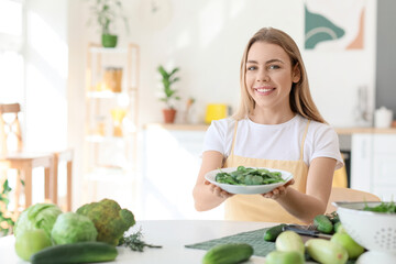 Young woman and plate with fresh salad in kitchen