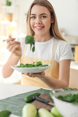 Obraz na płótnie Canvas Young woman eating fresh salad in kitchen
