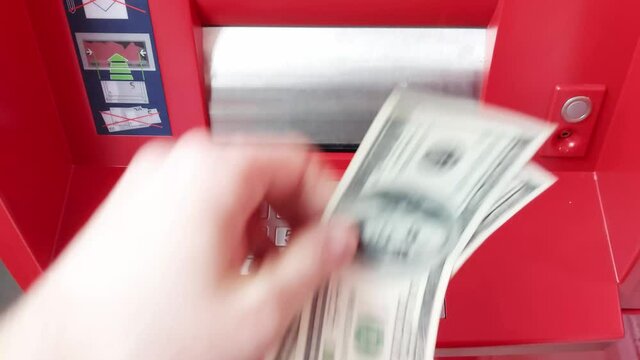 A man puts 2 dollar banknotes in a payment terminal for services. Loan repayment concept, close-up