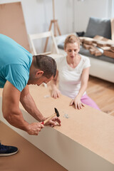 Husband and wife assembling new furniture - renovation home concept.